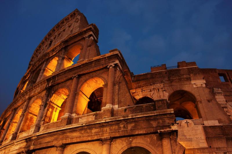 Low angel view of the Colosseum in Rome at dusk.